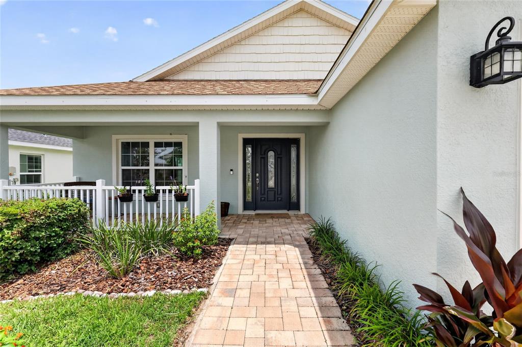 A paved walkway leads to the front entrance of a house with light green siding — 12591 NE 49TH DRIVE, OXFORD, FL