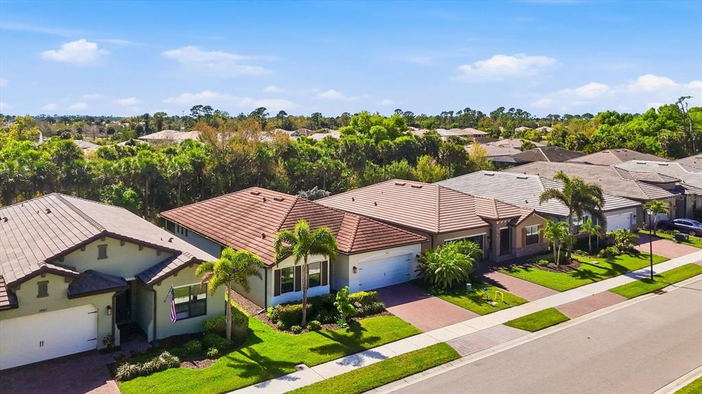 An aerial view shows a row of suburban houses with tiled roofs and green lawns — 12031 LOVEGRASS STREET, VENICE, FL