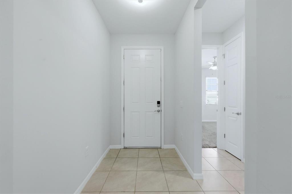 A tiled entryway features a white front door and a doorway leading to another room — 12031 LOVEGRASS STREET, VENICE, FL