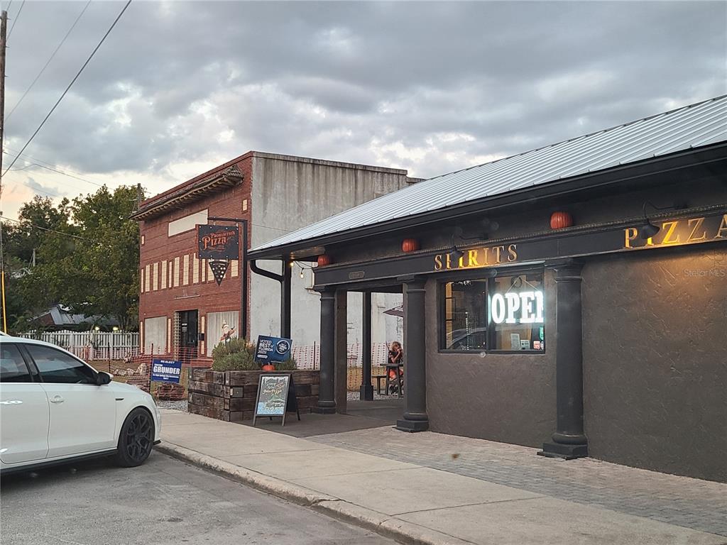 An exterior view of a pizza restaurant with a dark facade and a white car — NW 183 PLACE, HIGH SPRINGS, FL
