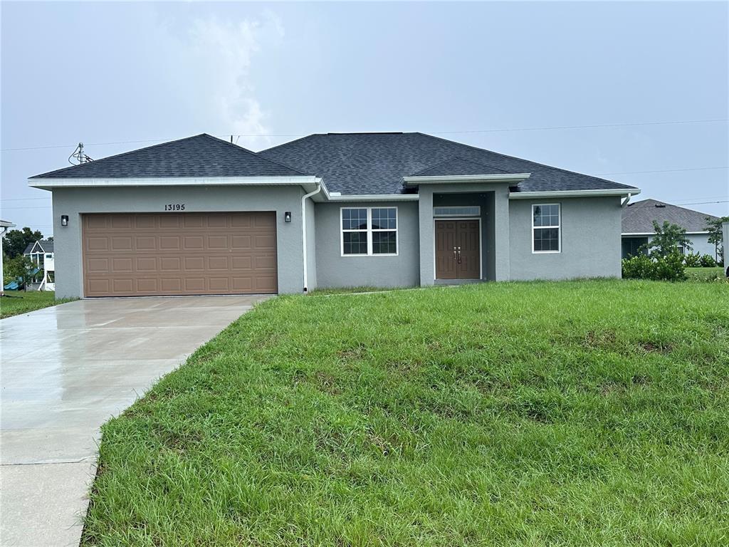 A single-story house with a gray stucco exterior, a brown garage door, and a shingled roof — 13195 DRYSDALE AVENUE, PORT CHARLOTTE, FL