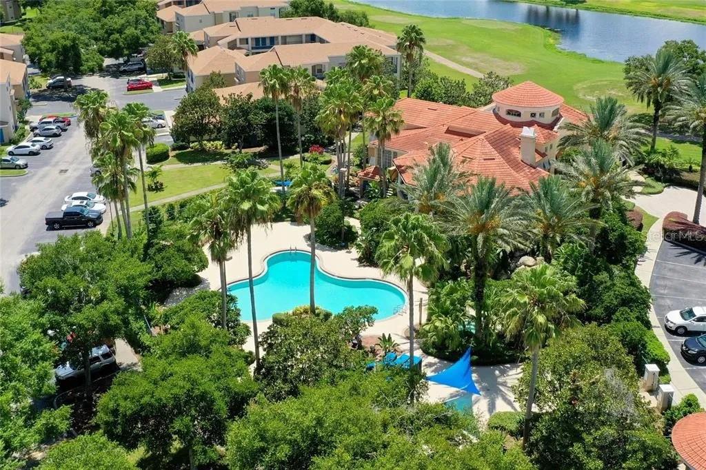 An aerial view shows a swimming pool surrounded by palm trees and a large building — 7310 WESTPOINTE BOULEVARD UNIT 623, ORLANDO, FL