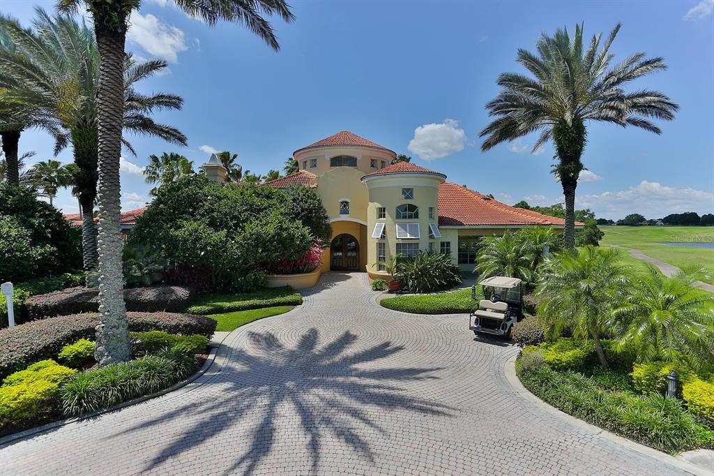 A paved circular driveway leads to the entrance of a Mediterranean-style home with palm trees — 7310 WESTPOINTE BOULEVARD UNIT 623, ORLANDO, FL