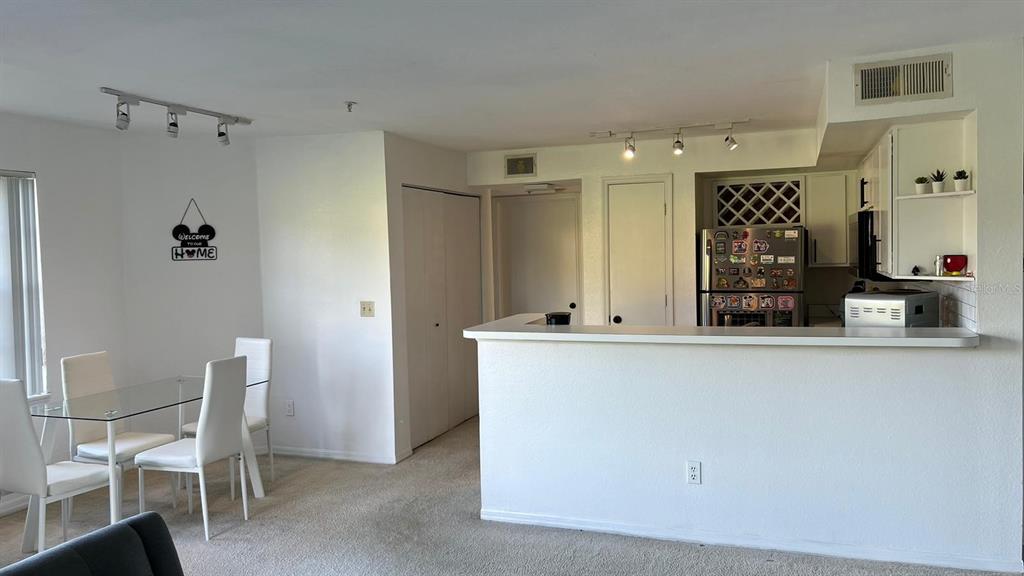 A dining area with a glass table and a kitchen with a breakfast bar — 7310 WESTPOINTE BOULEVARD UNIT 623, ORLANDO, FL