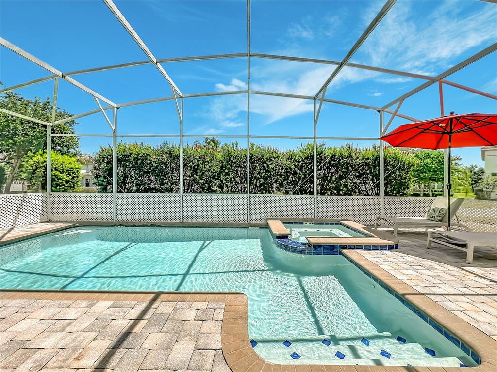 A screened-in swimming pool and spa feature a brick paver deck and a red umbrella — 1573 MAIDSTONE COURT, DAVENPORT, FL