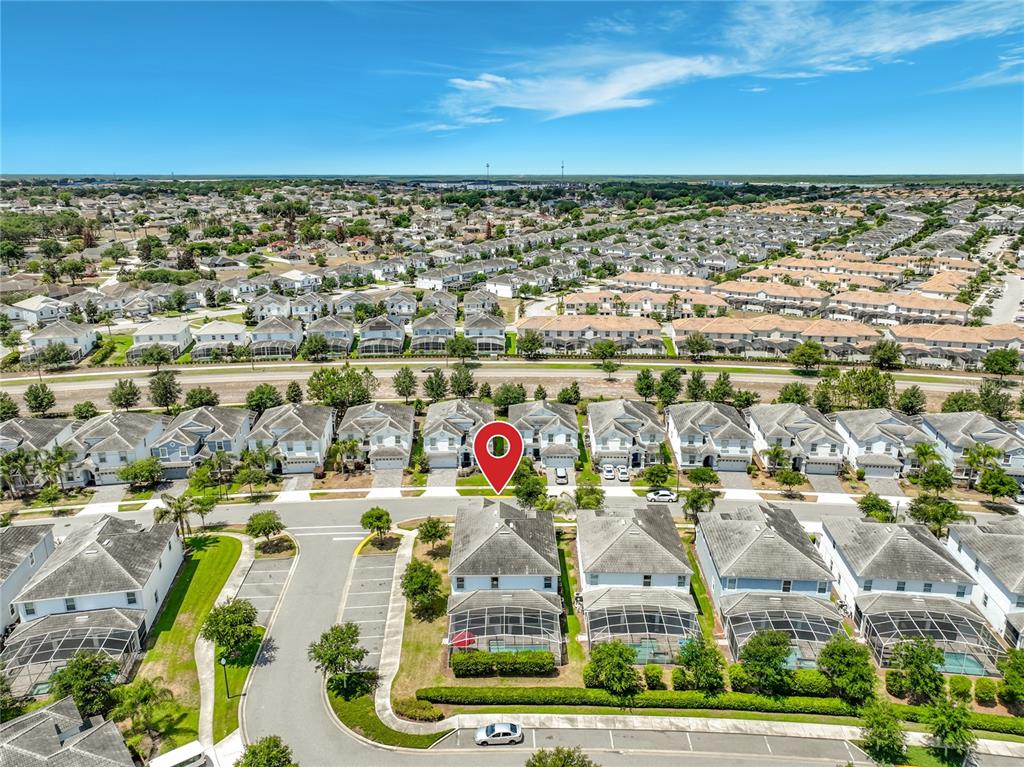An aerial view shows a suburban neighborhood with houses featuring screened-in pools and driveways — 1573 MAIDSTONE COURT, DAVENPORT, FL