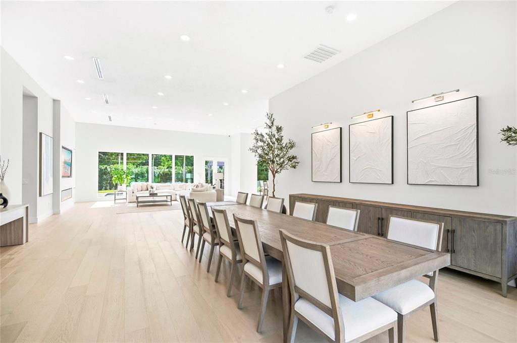 A spacious dining room features a long wooden table, upholstered chairs, and textured wall art — 1305 BELMONT DRIVE, ORLANDO, FL