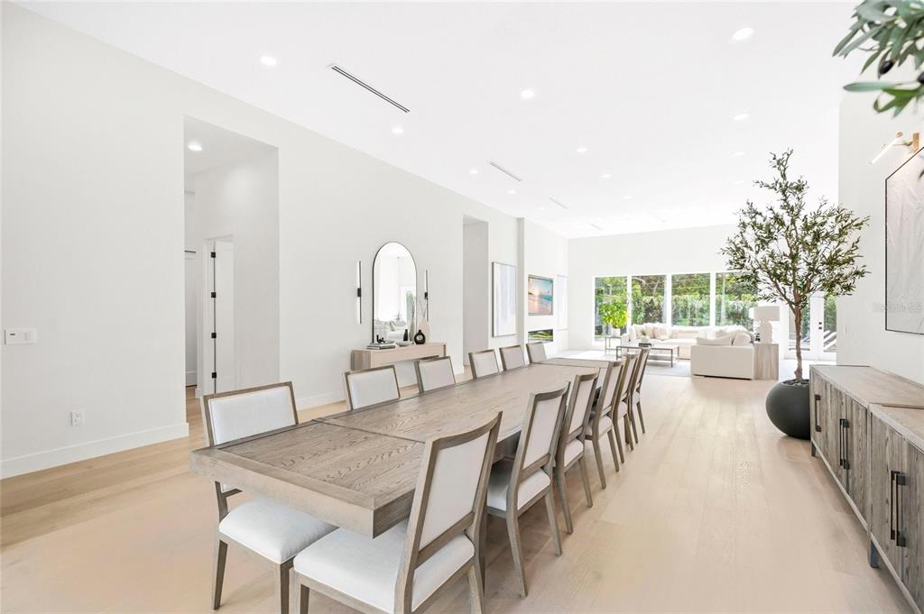 A bright dining room features a long wooden table, upholstered chairs, and light wood flooring — 1305 BELMONT DRIVE, ORLANDO, FL