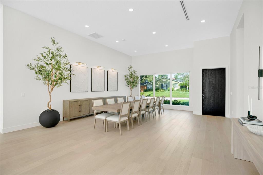 A bright dining room features a long wooden table, light wood floors, and white walls — 1305 BELMONT DRIVE, ORLANDO, FL