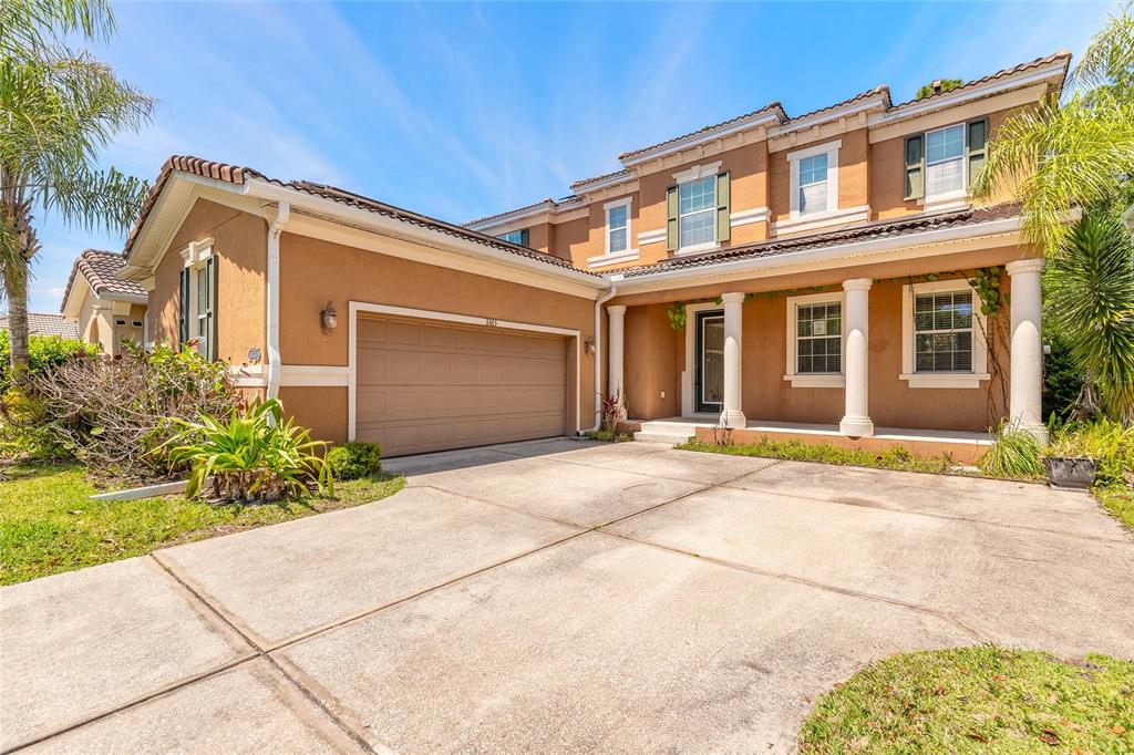 A two-story tan stucco house with a two-car garage and a covered front porch — 3365 PEGASO AVENUE, NEW SMYRNA BEACH, FL