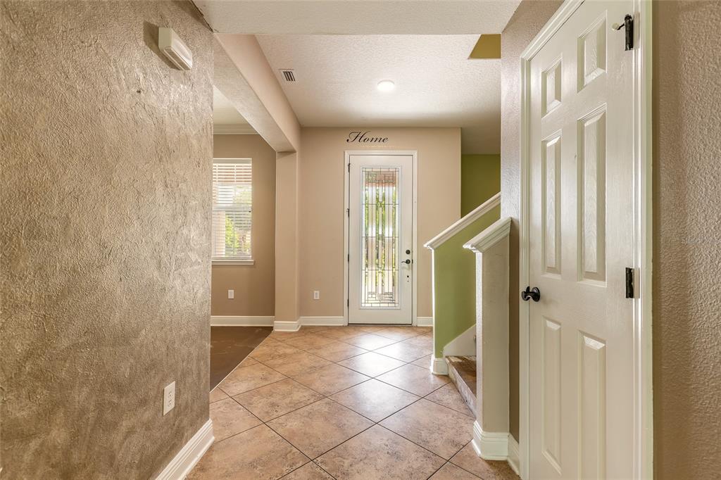 An entryway with tiled floors, a front door with glass inlay, and a staircase — 3365 PEGASO AVENUE, NEW SMYRNA BEACH, FL