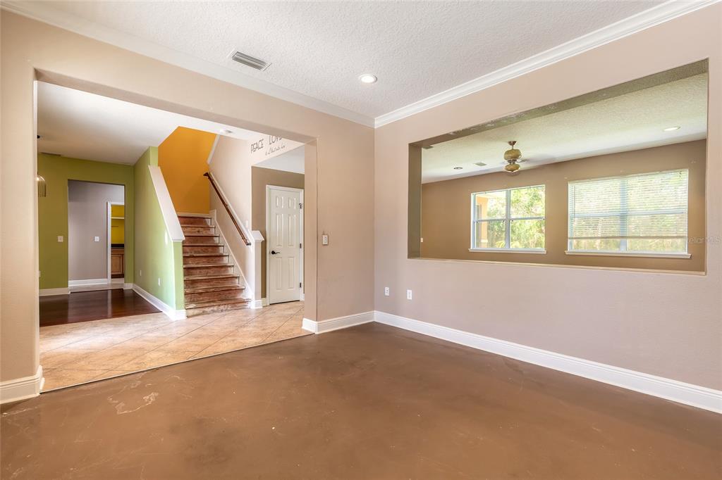 An interior view showing a room with brown flooring, a staircase, and a large wall cutout — 3365 PEGASO AVENUE, NEW SMYRNA BEACH, FL