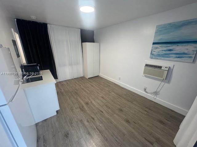 A small room features light wood-look flooring, a white kitchenette, a wardrobe, and wall art — 9920 Collins Ave # 23, Bal Harbour FL 33154, BAL HARBOUR, FL