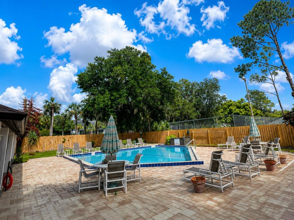 A swimming pool with lounge chairs and a patio area surrounded by a wooden fence — 2477 TAHOE CIRCLE UNIT 2477, WINTER PARK, FL