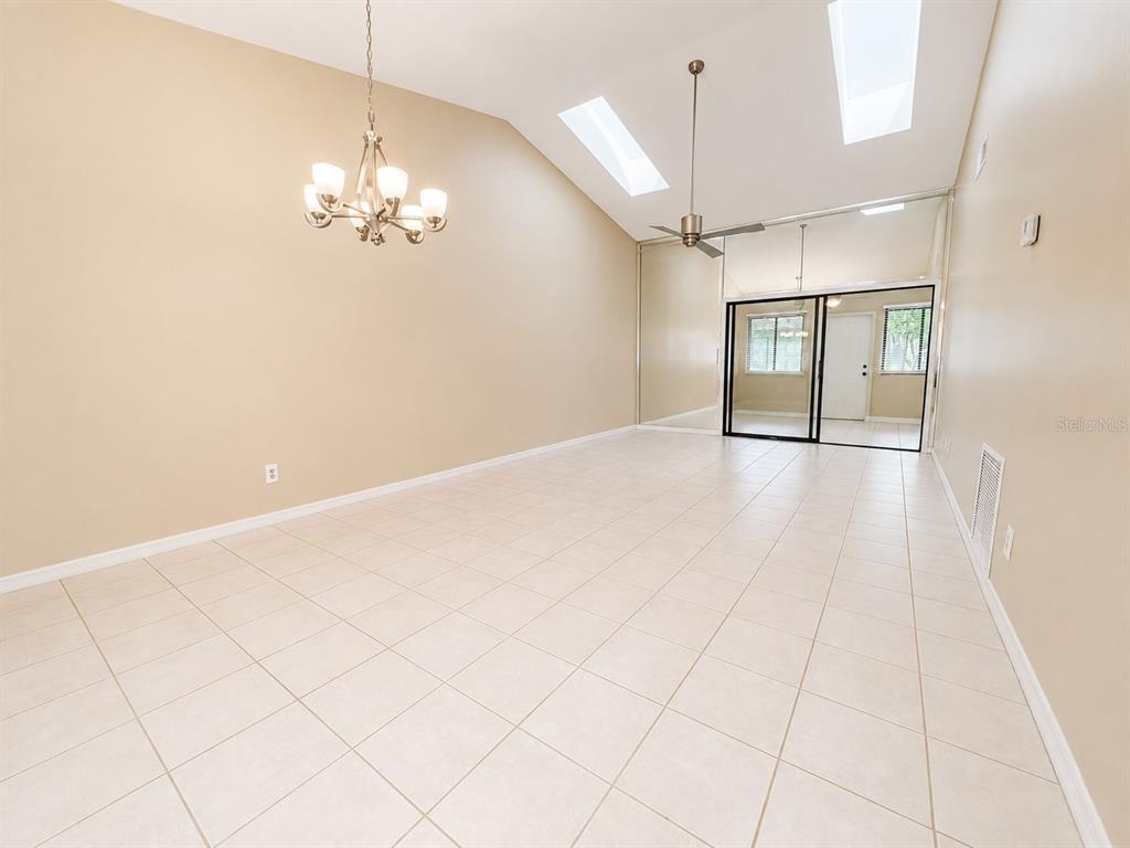 A room with beige walls, tile flooring, a vaulted ceiling, skylights, and a mirrored wall — 2477 TAHOE CIRCLE UNIT 2477, WINTER PARK, FL