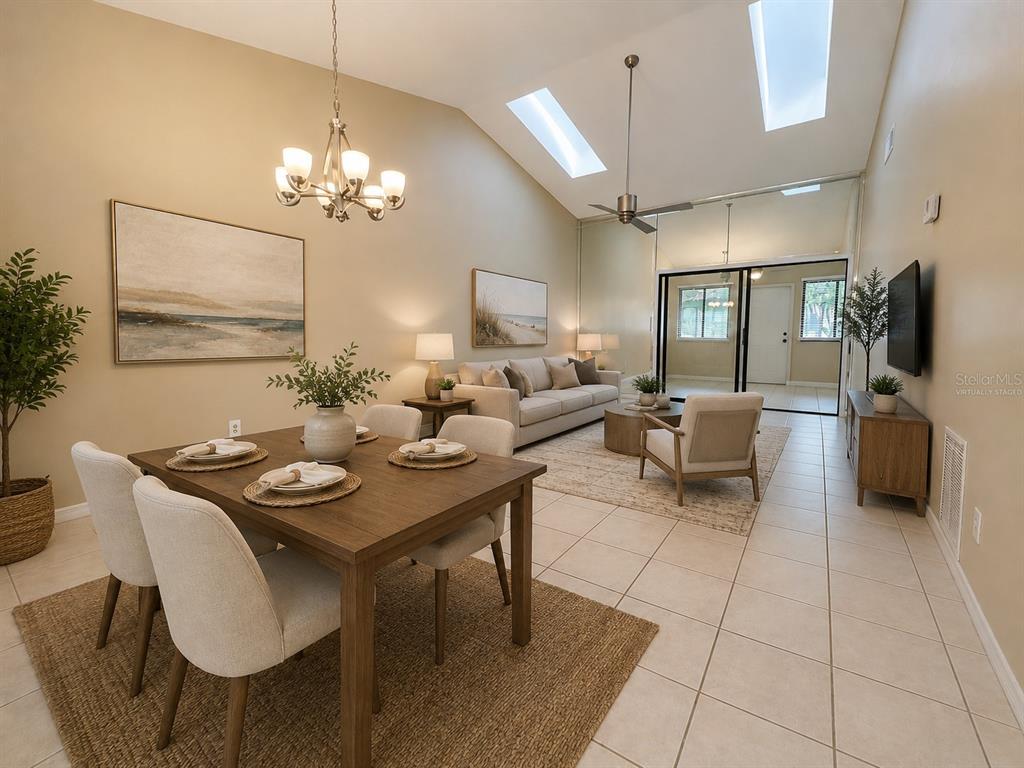 A living and dining area with vaulted ceilings, skylights, tile floors, and neutral furniture — 2477 TAHOE CIRCLE UNIT 2477, WINTER PARK, FL