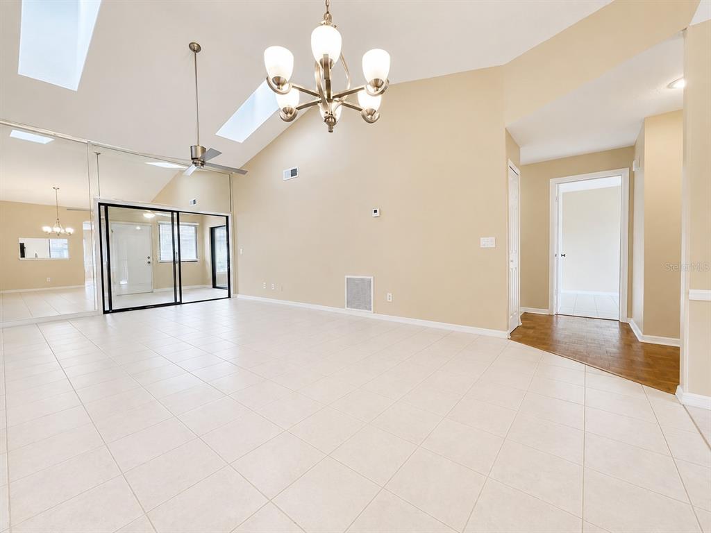 A spacious living room features vaulted ceilings, tile flooring, a chandelier, and mirrored wall panels — 2477 TAHOE CIRCLE UNIT 2477, WINTER PARK, FL