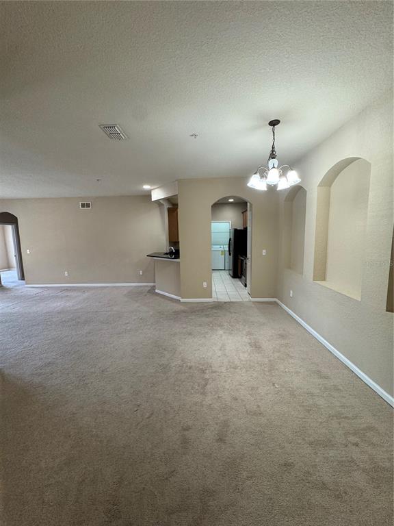 A carpeted living area features an arched entryway leading to a kitchen with tile flooring — 3331 WHITESTONE CIRCLE UNIT 101, KISSIMMEE, FL
