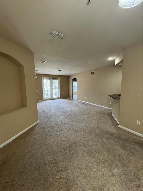 An open living area features beige carpet, tan walls, a recessed wall niche, and glass doors — 3331 WHITESTONE CIRCLE UNIT 101, KISSIMMEE, FL