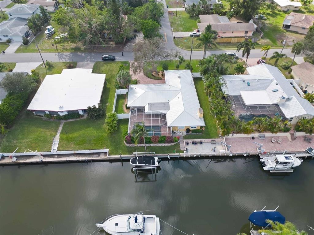An aerial view shows a waterfront house with a pool cage and a private dock — 6711 AVENUE C, SARASOTA, FL