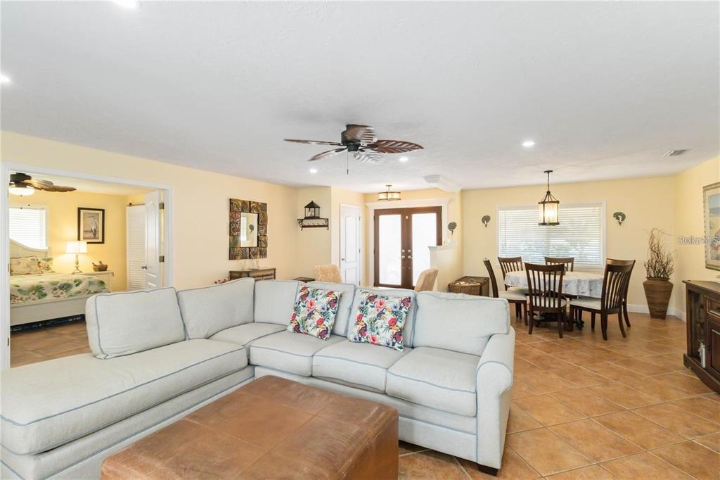 A living room with a sectional sofa and a dining area with tile flooring — 6711 AVENUE C, SARASOTA, FL