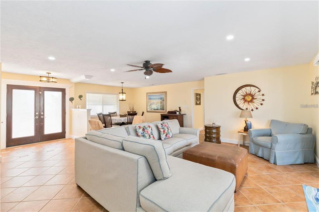 A living room with tile floors, a sectional sofa, and a dining area in the background — 6711 AVENUE C, SARASOTA, FL
