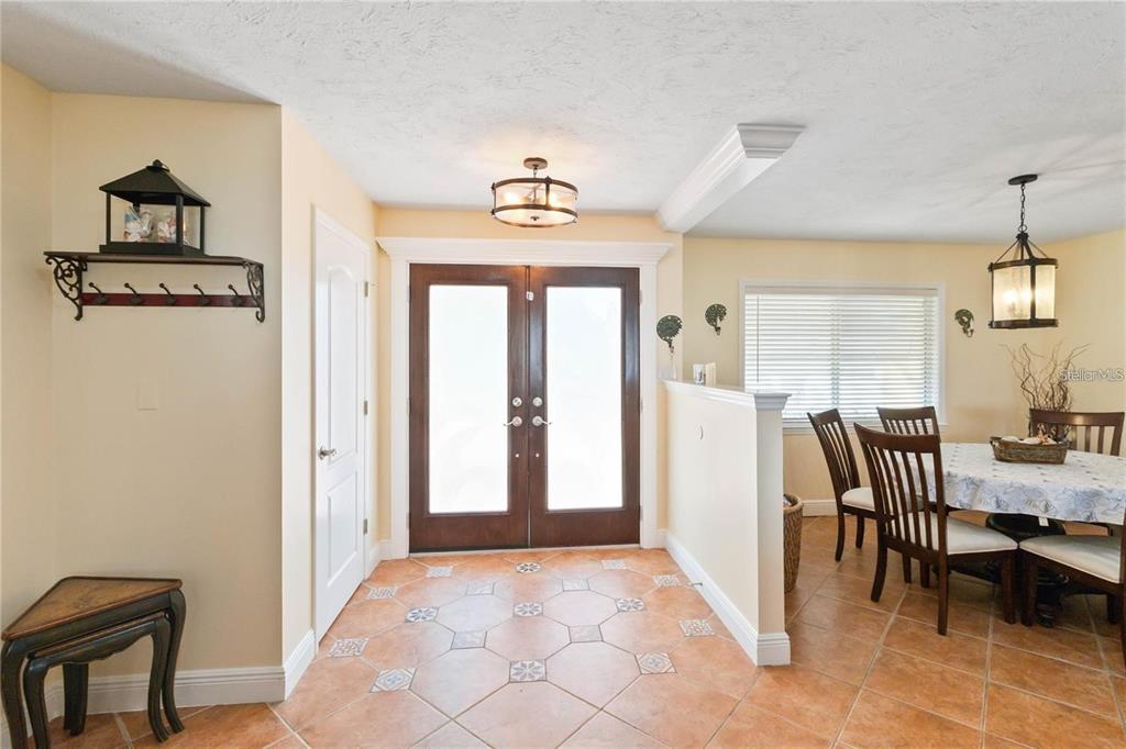 An entryway with tile flooring leads to double front doors next to a dining area — 6711 AVENUE C, SARASOTA, FL