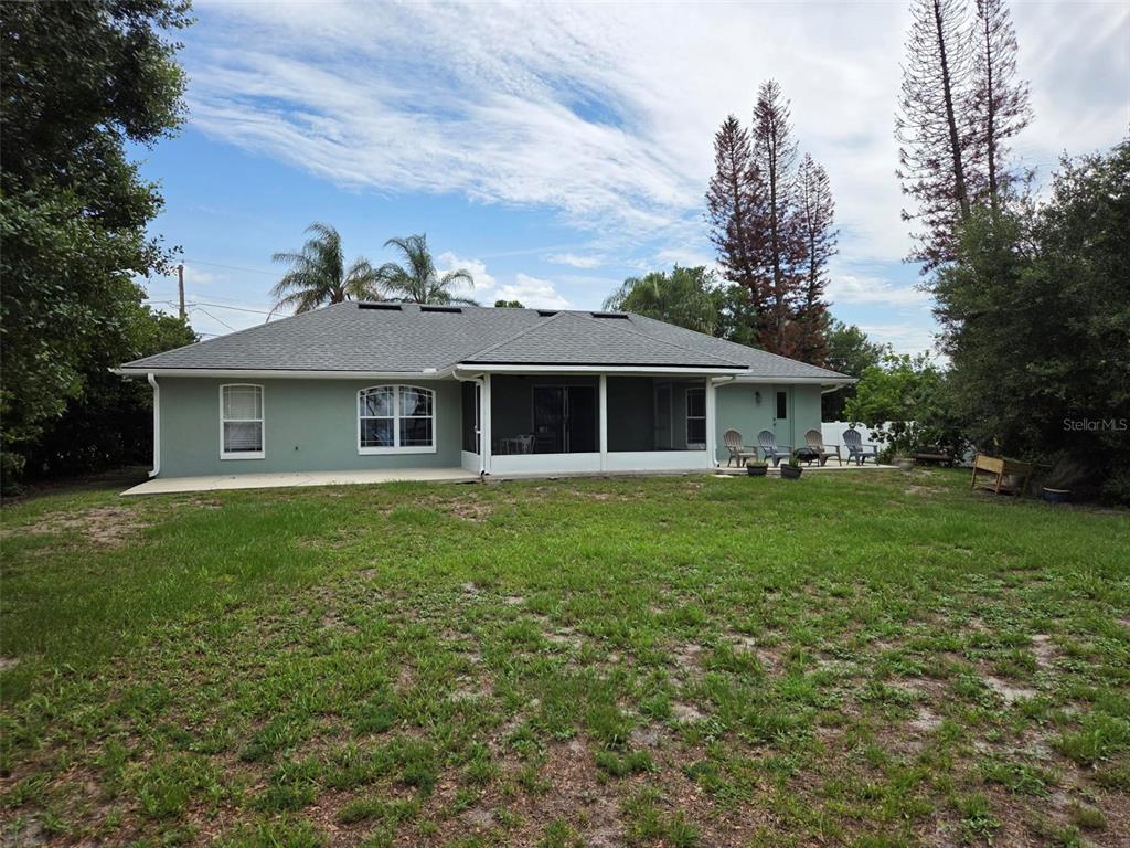 A grassy lawn overlooks a lake at sunset with tall pine trees and marshy vegetation — 2562 TRAVIDA DRIVE, DELTONA, FL