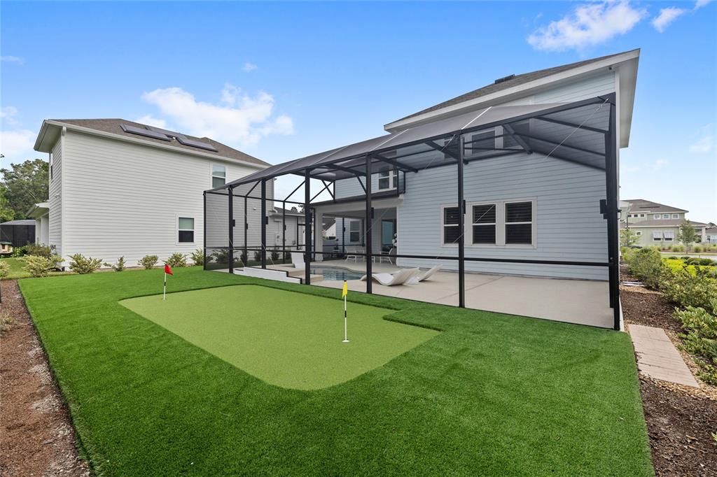 A backyard features a putting green with two flags, a screened-in patio, and a pool — 3126 VANGUARD COURT, ST CLOUD, FL