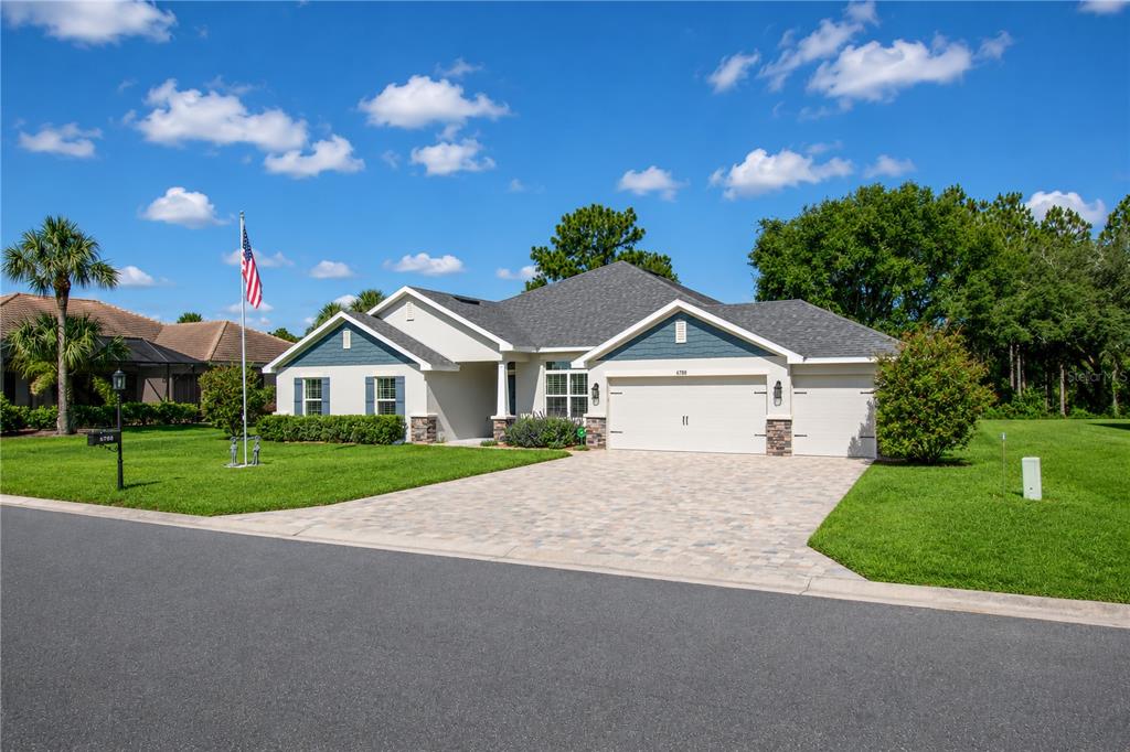 A single-story house with a blue-accented gable, a paved driveway, and a flag pole — 6788 SW 179TH AVENUE ROAD, DUNNELLON, FL