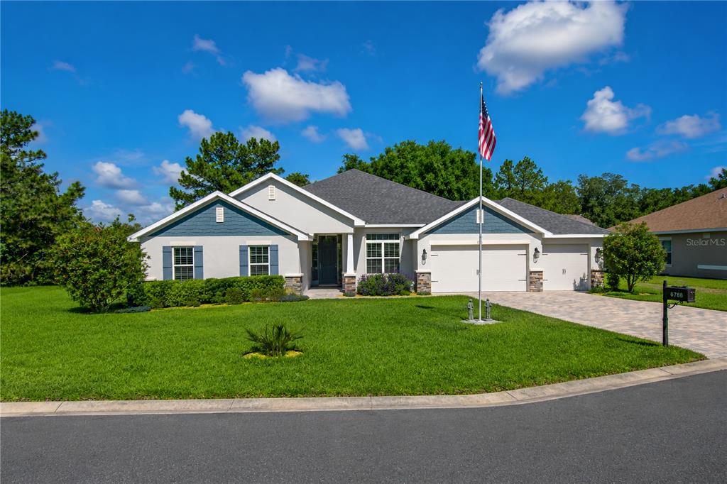A single-story suburban house with a blue-accented exterior, a two-car garage, and a flag pole — 6788 SW 179TH AVENUE ROAD, DUNNELLON, FL