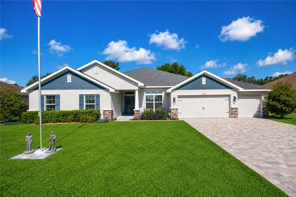 A single-story house with a blue-accented exterior, a paved driveway, and a flagpole — 6788 SW 179TH AVENUE ROAD, DUNNELLON, FL
