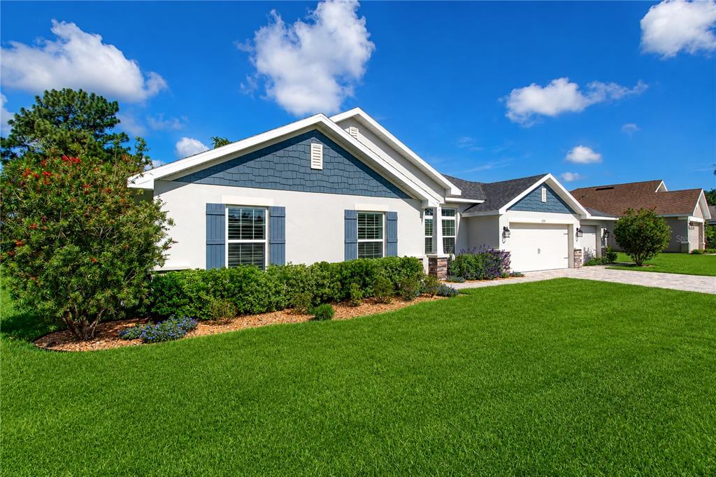 A single-story house with blue shingle siding, white stucco walls, and a two-car garage — 6788 SW 179TH AVENUE ROAD, DUNNELLON, FL