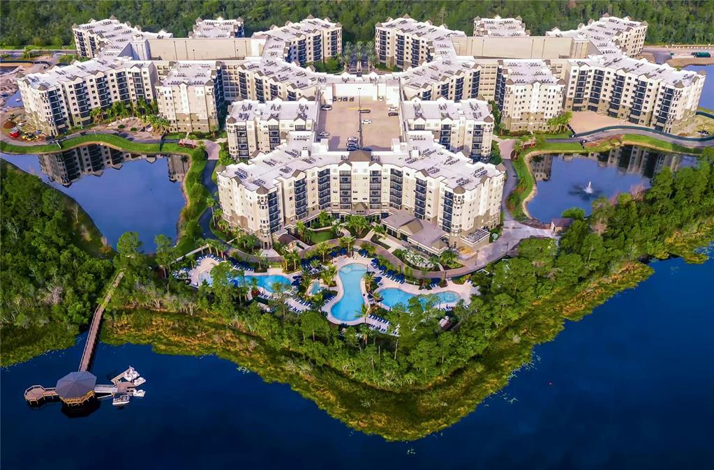 Aerial view of a large multi-story apartment complex surrounding a central pool and lake — 14501 GROVE RESORT AVENUE UNIT 1105, WINTER GARDEN, FL