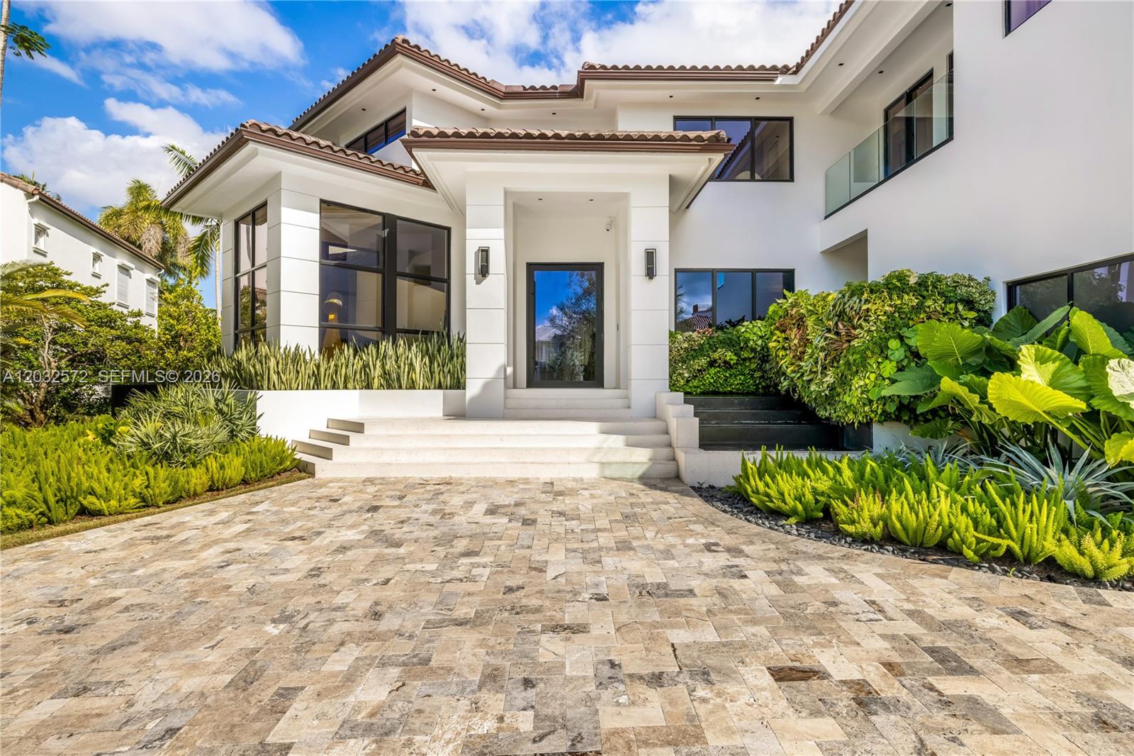 A modern two-story house with a paved driveway, white exterior, and lush green landscaping — 199 Caoba Ct, Coral Gables FL 33143, CORAL GABLES, FL