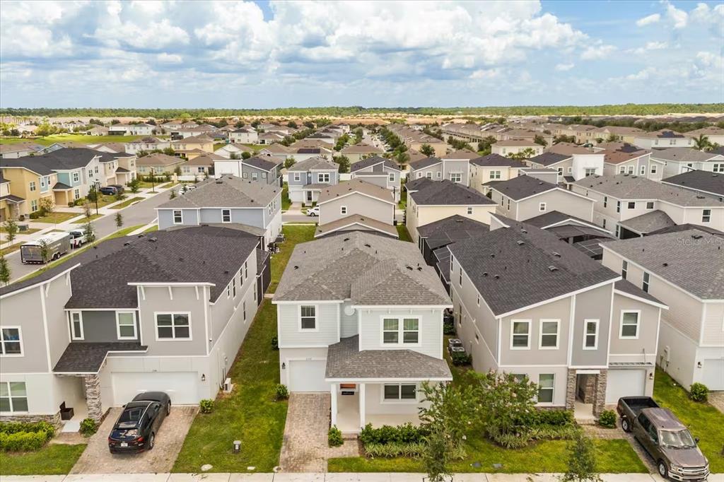 An aerial view shows three suburban houses with gray roofs and driveways in a neighborhood — 2337 SALTY WINDS WAY, KISSIMMEE, FL
