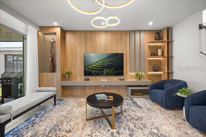 A modern living room features a wood-paneled media wall, blue armchairs, and a patterned rug — 2337 SALTY WINDS WAY, KISSIMMEE, FL
