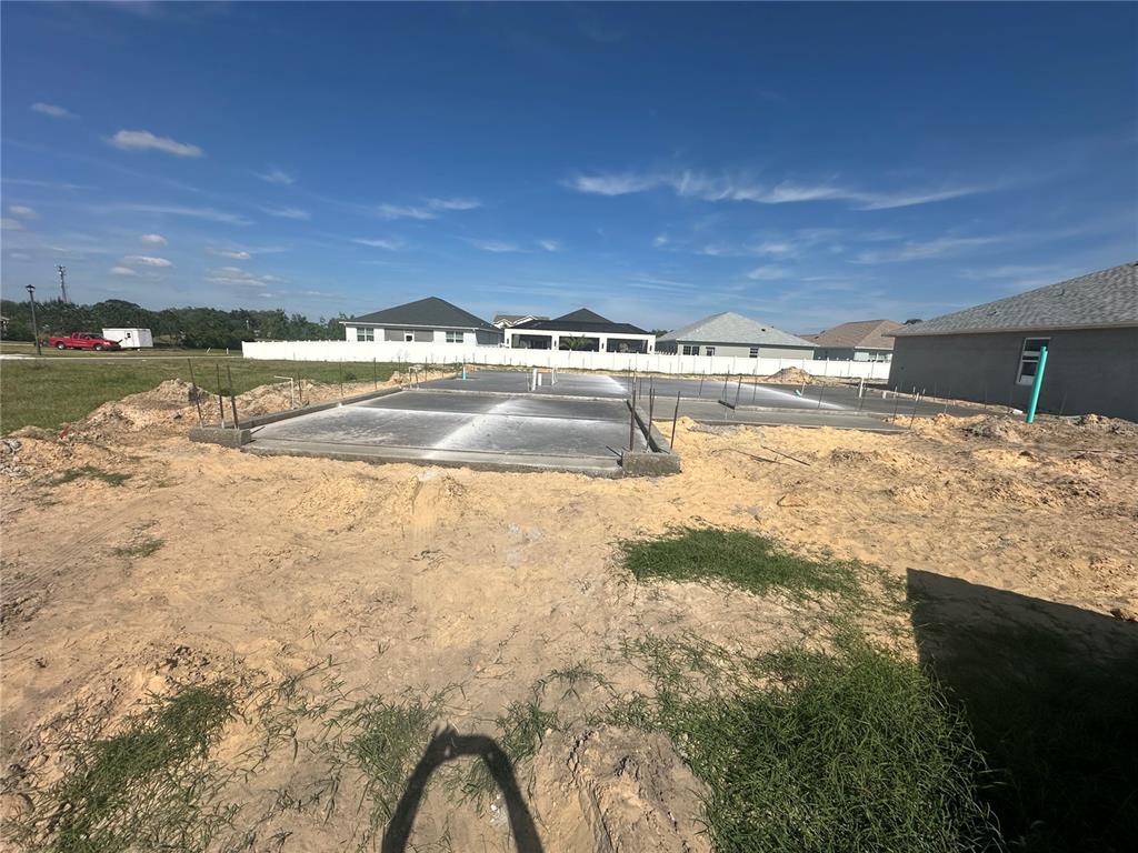 A concrete slab foundation for a new house sits on a sandy residential lot — 12609 NE 48TH STREET, OXFORD, FL