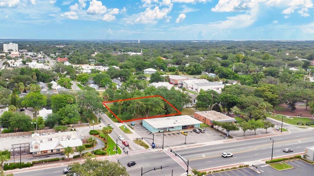 An aerial view shows a vacant, tree-covered lot outlined in red next to commercial buildings — 00 LAUREL AVENUE, SANFORD, FL