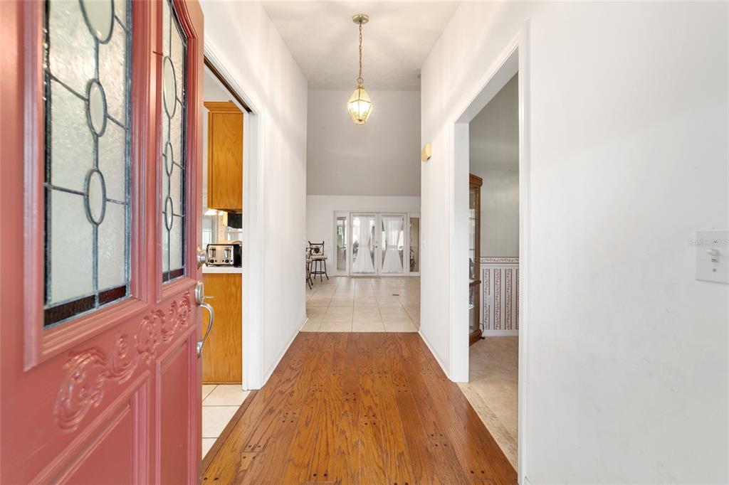 An entryway with hardwood floors leads to a tiled living area with glass doors — 4807 SE 14TH STREET, OCALA, FL