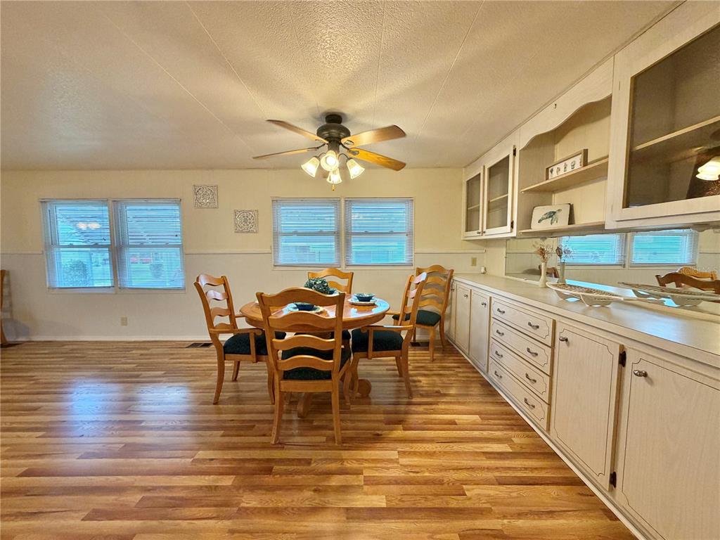 A dining room features wood-look flooring, a round table with chairs, and built-in white cabinetry — 115 GARDENIA WAY, LEESBURG, FL