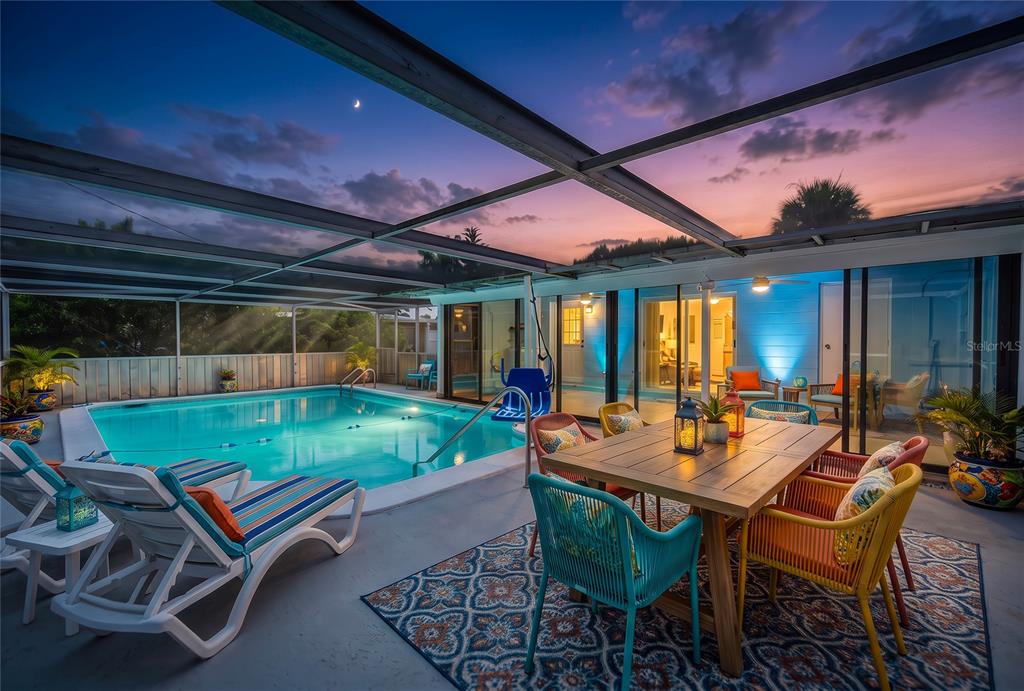 A screened-in pool patio features a dining set, lounge chairs, and a sunset view — 8158 AGRESS AVENUE, NORTH PORT, FL