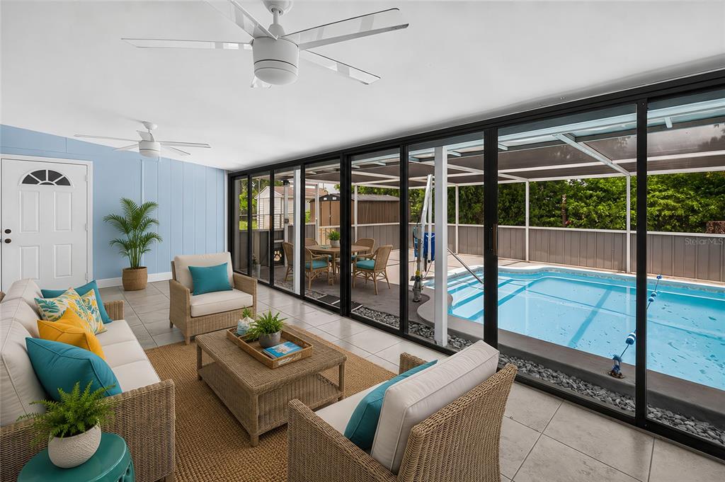 A sunroom with wicker furniture and tile floors overlooks a screened-in swimming pool — 8158 AGRESS AVENUE, NORTH PORT, FL