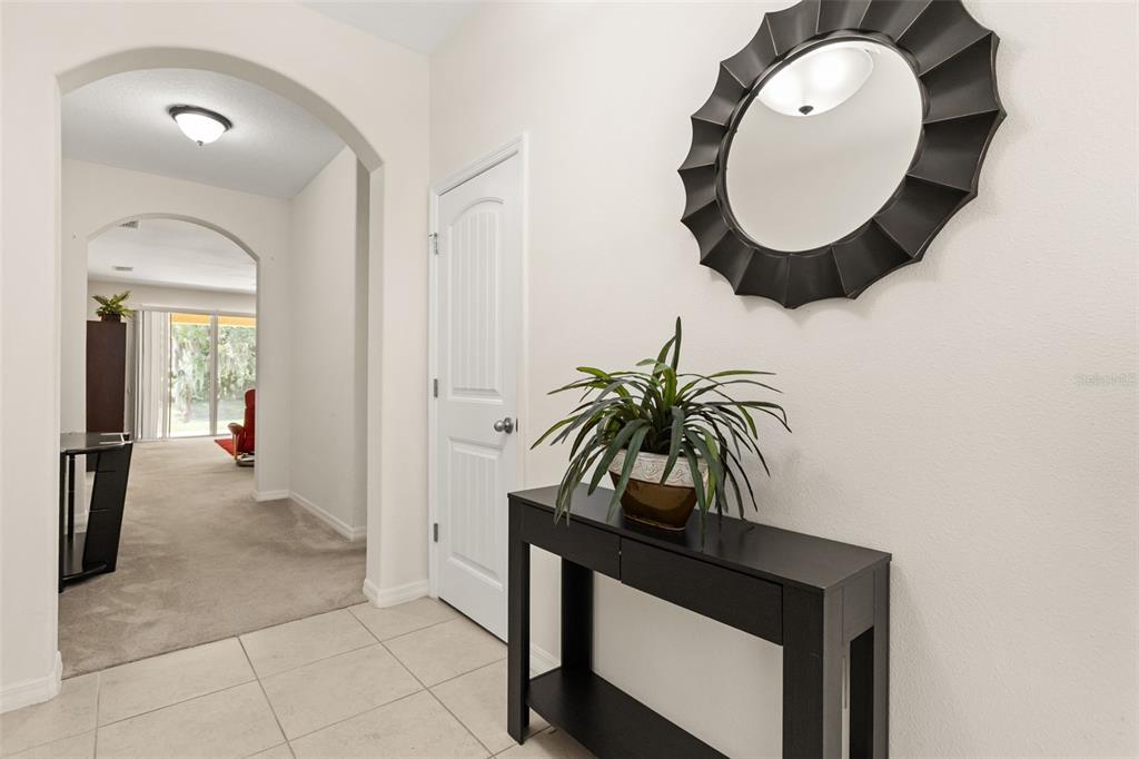 A tiled entryway features a black console table, a round mirror, and an arched doorway — 3737 CHANDLER ESTATES DRIVE, APOPKA, FL
