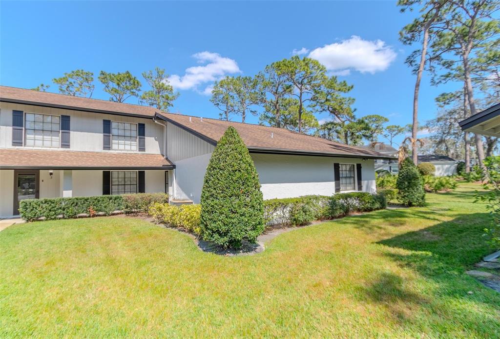 A two-story townhouse exterior with white siding, black shutters, and a manicured lawn — 5434 SADDLEBROOK WAY UNIT 3, WESLEY CHAPEL, FL