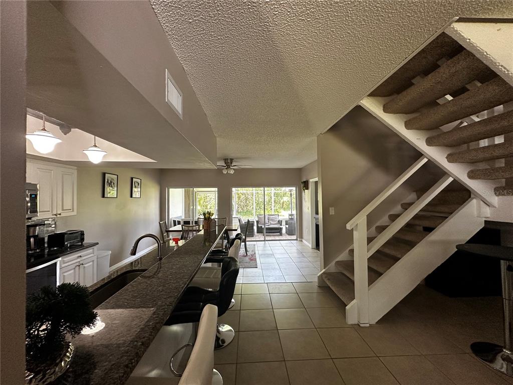 A kitchen with a breakfast bar overlooks a dining area and a staircase with carpeted steps — 5434 SADDLEBROOK WAY UNIT 3, WESLEY CHAPEL, FL