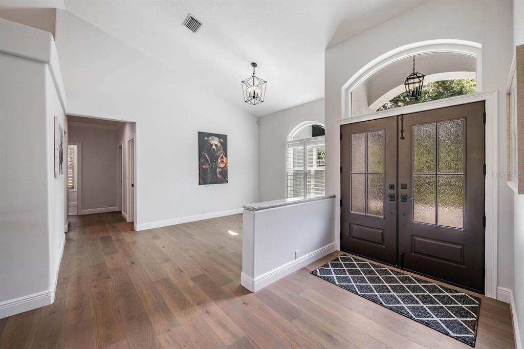 An entryway with hardwood floors, a half wall, double front doors, and a bear portrait — 17833 HYLAND LANE, DADE CITY, FL