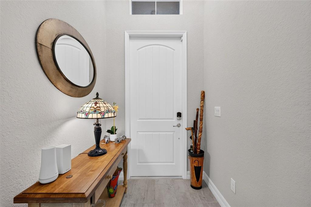 An entryway features a wooden console table, a stained-glass lamp, a mirror, and a door — 11825 PERENNIAL PLACE, BRADENTON, FL