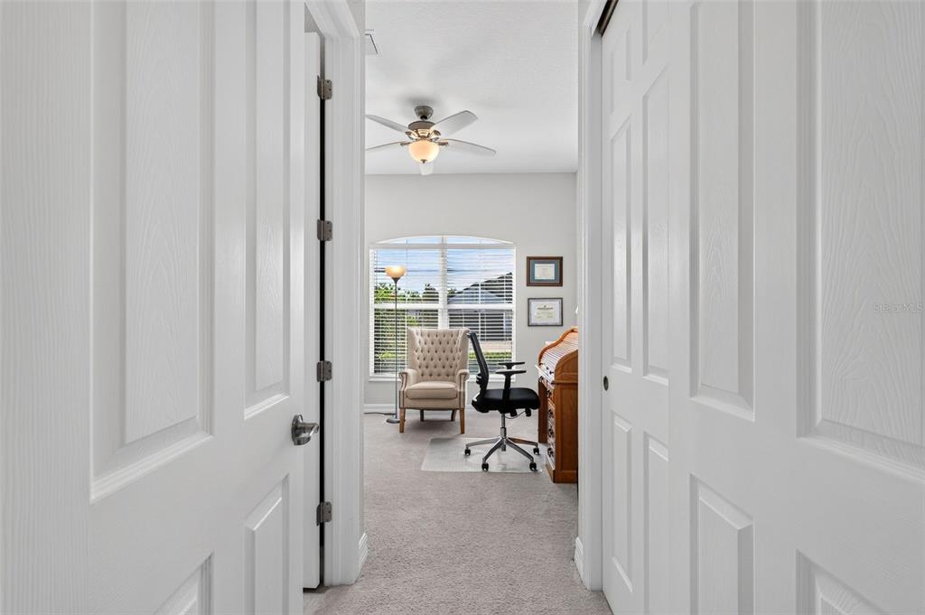 A view through a doorway into a carpeted home office with a desk and chair — 11825 PERENNIAL PLACE, BRADENTON, FL