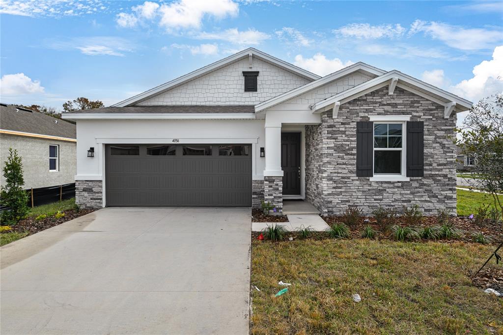 A single-story house features a gray stone facade, white siding, and a two-car garage — 4056 BANNOCK AVENUE, TAVARES, FL